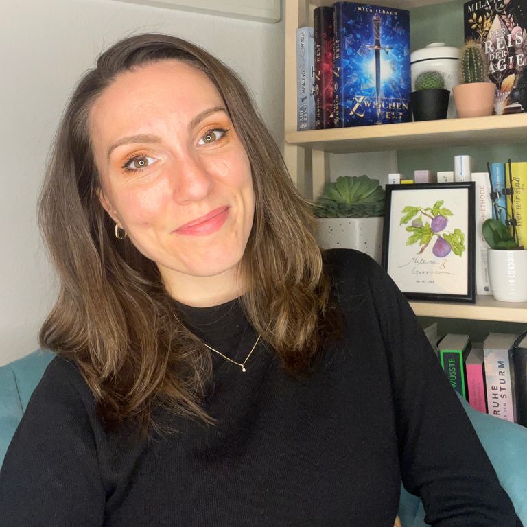 Mila Ilbach lächelt, im Hintergrund ein Bücherregal mit ihren Veröffentlichungen.
