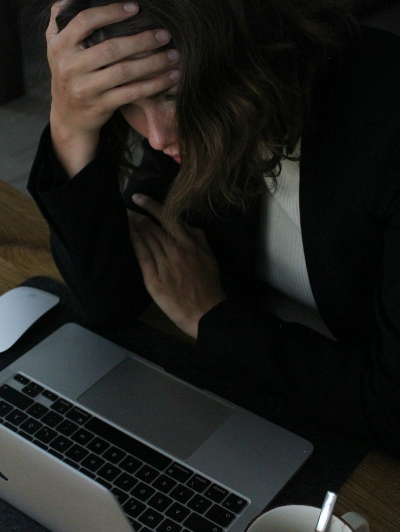 Eine Frau sitzt vor ihrem Laptop und scheint erschöpft.