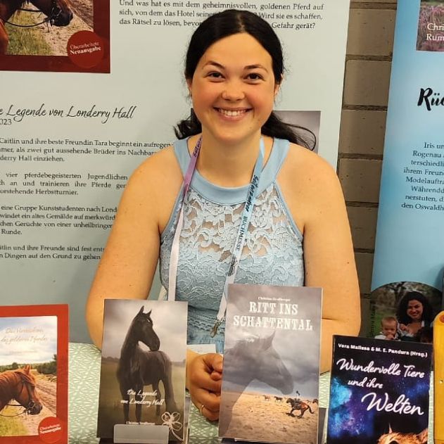 Christina Straßberger auf einer Buchmesse mit ihren veröffentlichten Büchern: Ritt ins Schattental, Die Legende von Loderry Hall u.a.